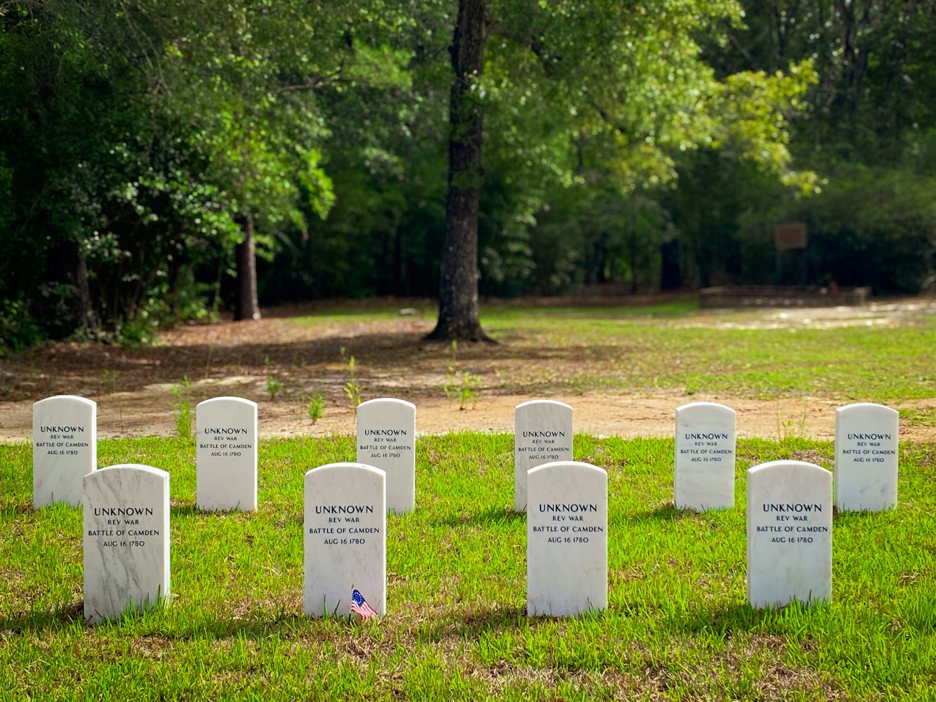 Rows of white gravestones in a grassy field.