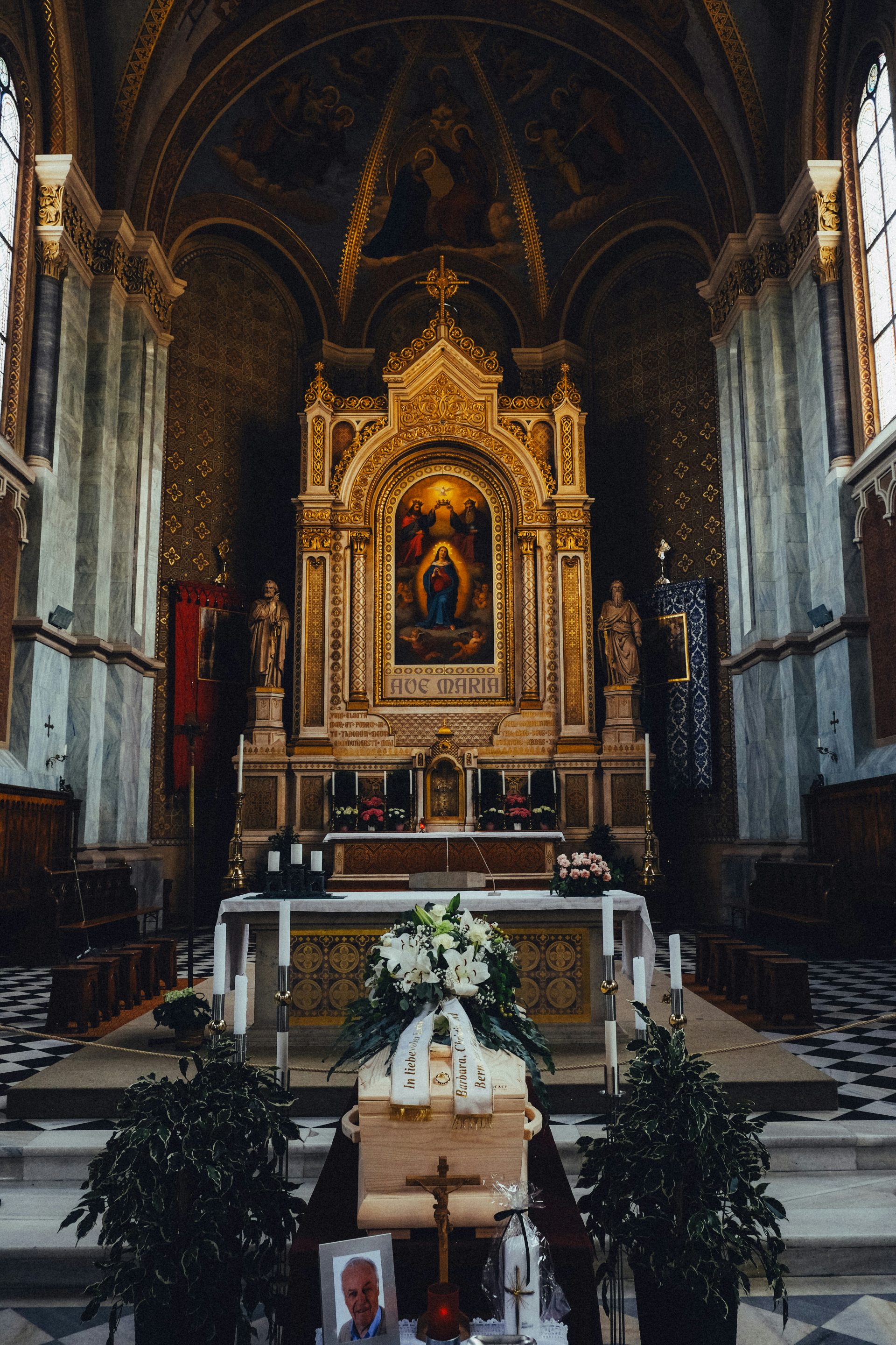 A coffin decorated with flowers in a church altar.